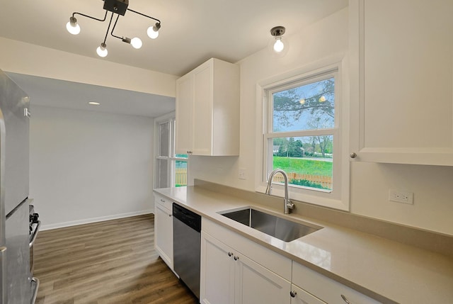 kitchen featuring dark wood-style flooring, stainless steel dishwasher, a sink, light countertops, and white cabinetry