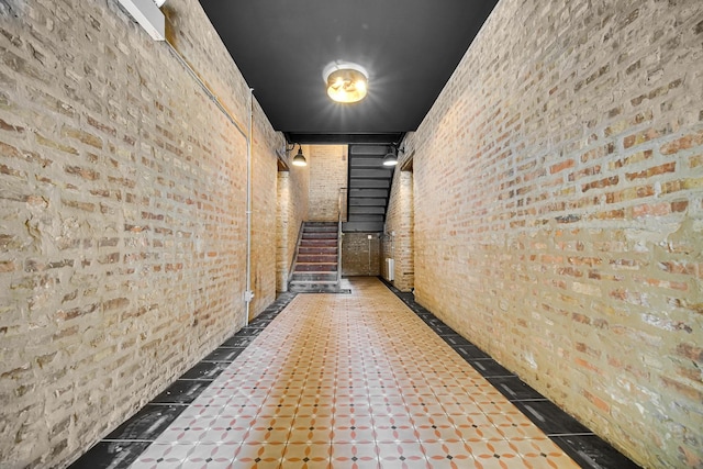 corridor featuring stairs and brick wall