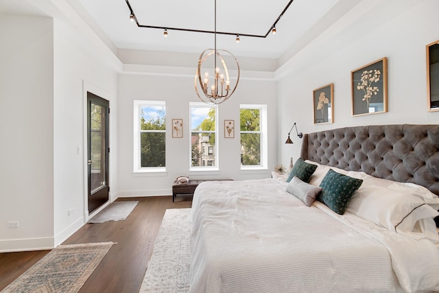 bedroom with track lighting, a chandelier, and multiple windows