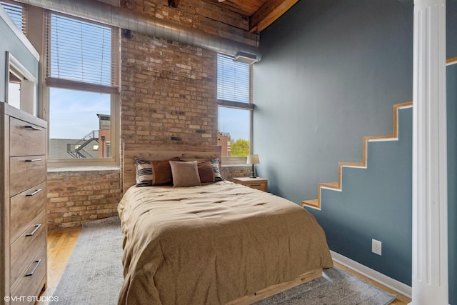 bedroom featuring wood finished floors and brick wall