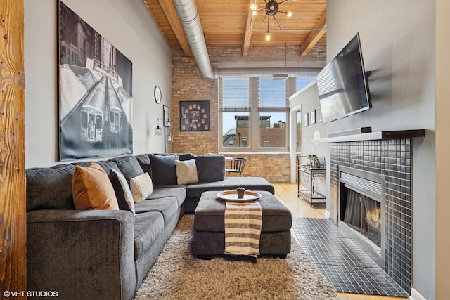 living room featuring a tile fireplace, wooden ceiling, wood finished floors, and beam ceiling