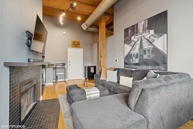 living room with a high ceiling, a fireplace, wood ceiling, and wood finished floors
