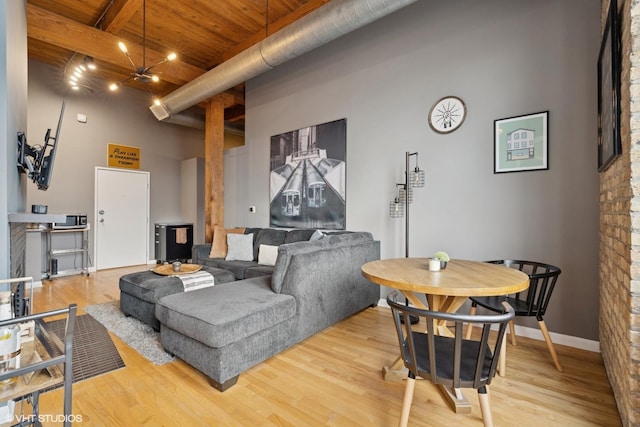living room with a towering ceiling, wood ceiling, baseboards, and wood finished floors