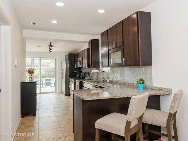 3004 N Olcott Ave, Chicago, IL 60707 - kitchen with stainless steel appliances, a sink, dark brown cabinets, backsplash, and light stone counters