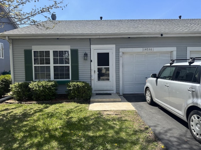 view of front of property featuring a front lawn, roof with shingles, and a garage