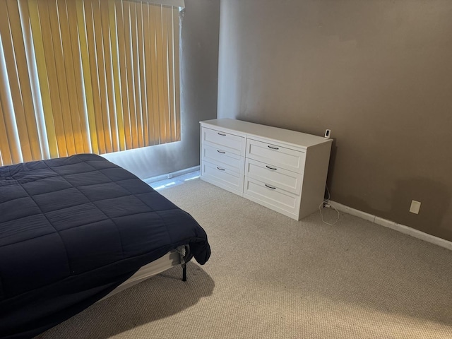 bedroom featuring baseboards and light colored carpet