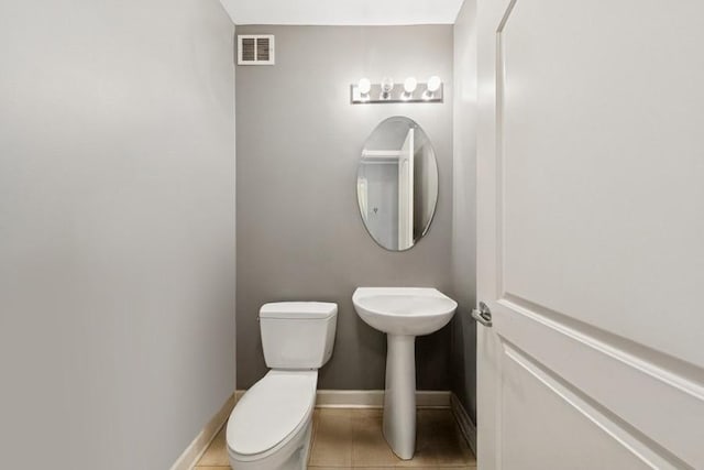 half bathroom featuring toilet, baseboards, a sink, and tile patterned flooring