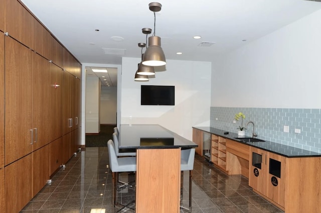 kitchen featuring a sink, a breakfast bar, modern cabinets, tasteful backsplash, and hanging light fixtures