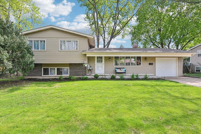 split level home with a garage, driveway, a front yard, a chimney, and brick siding