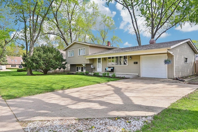 tri-level home with a garage, driveway, a front lawn, and a chimney