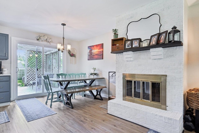 dining area featuring wood finished floors, a chandelier, a fireplace, and baseboards