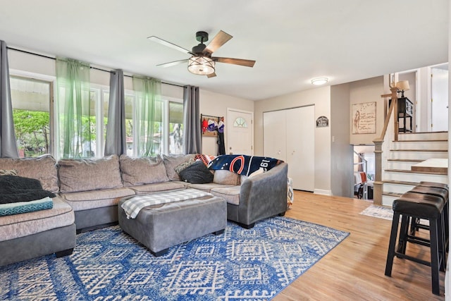 living room featuring wood finished floors, ceiling fan, stairway, and baseboards