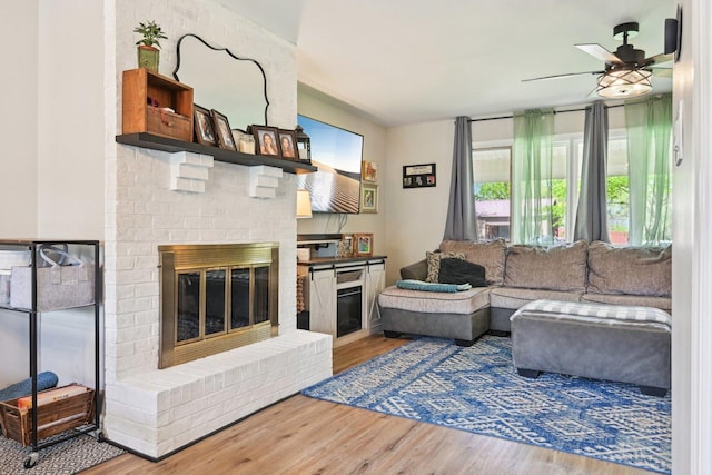 living area featuring wood finished floors, ceiling fan, and a fireplace