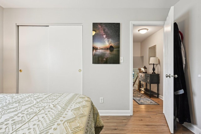 bedroom with light wood finished floors, baseboards, and a closet