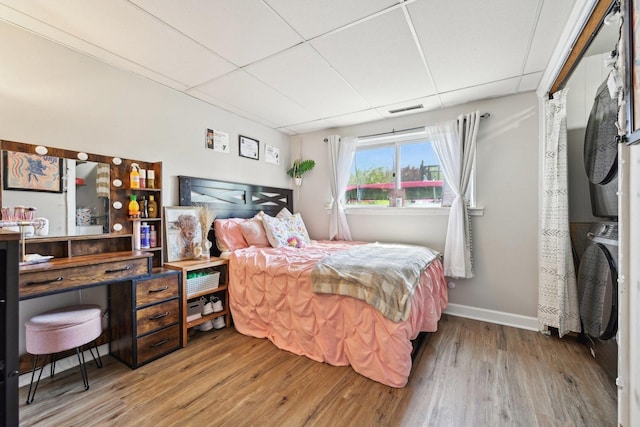 bedroom featuring wood finished floors, a drop ceiling, and baseboards