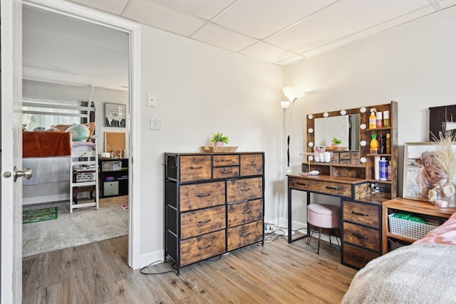 bedroom with wood finished floors and a drop ceiling
