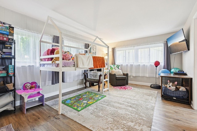 bedroom with wood finished floors, multiple windows, and baseboards