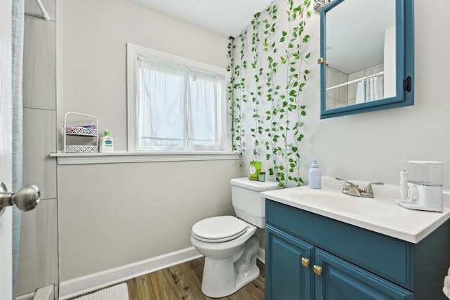 bathroom with wood finished floors, toilet, vanity, and baseboards