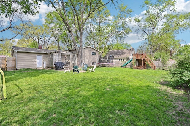 view of yard featuring a playground, a trampoline, and a fire pit