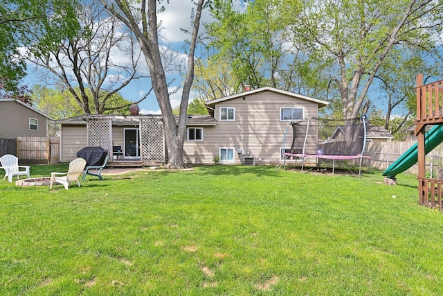 rear view of property with a trampoline, a playground, an outdoor fire pit, and central air condition unit