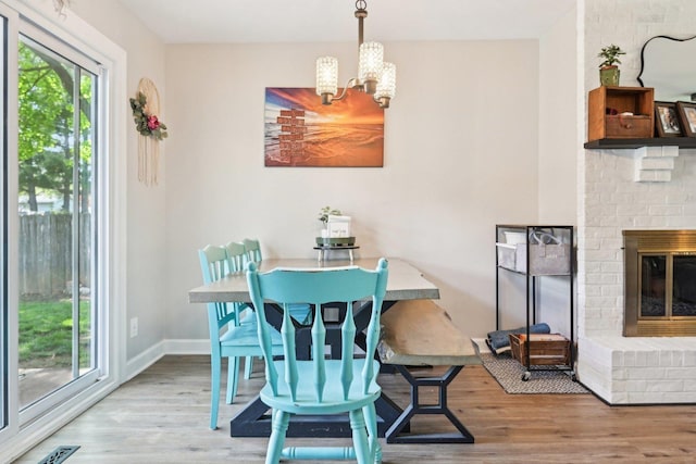 dining space with a chandelier, wood finished floors, baseboards, and a fireplace