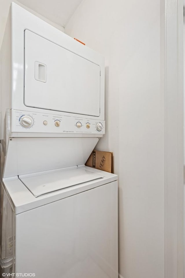 clothes washing area with stacked washer and dryer and laundry area