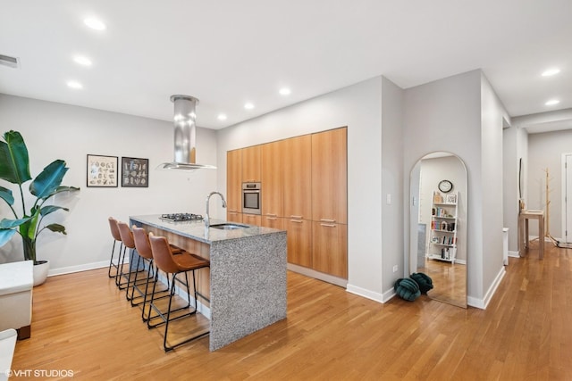 kitchen with a sink, extractor fan, stainless steel appliances, a kitchen bar, and modern cabinets