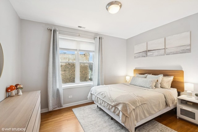 bedroom featuring visible vents, baseboards, and wood finished floors