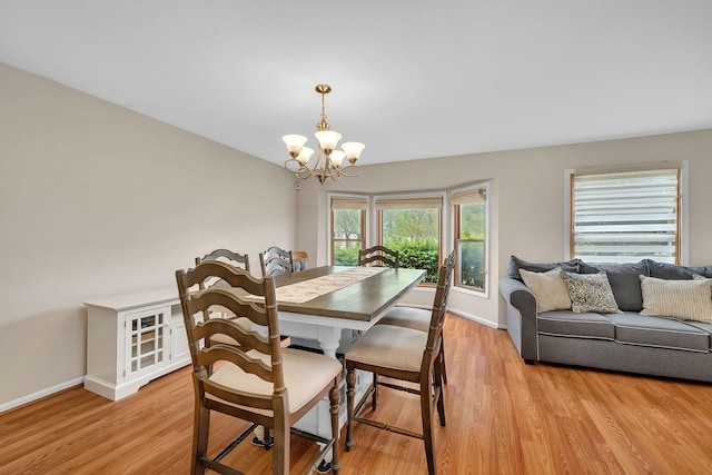 dining space with baseboards, an inviting chandelier, and light wood-style floors