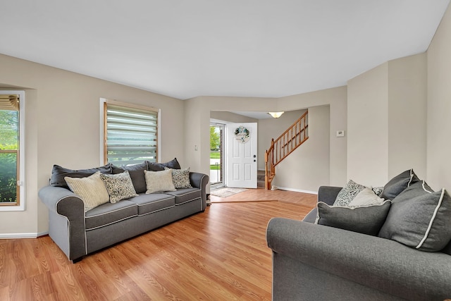 living room with baseboards, stairway, and light wood-type flooring