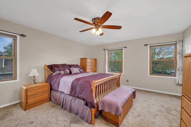 bedroom featuring baseboards, ceiling fan, light carpet, and multiple windows
