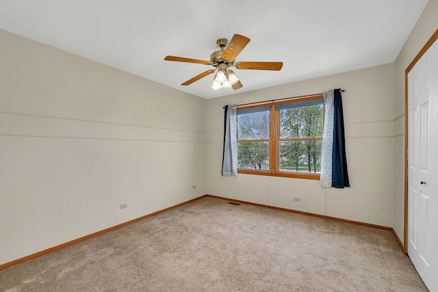 carpeted empty room featuring baseboards, a ceiling fan, and visible vents