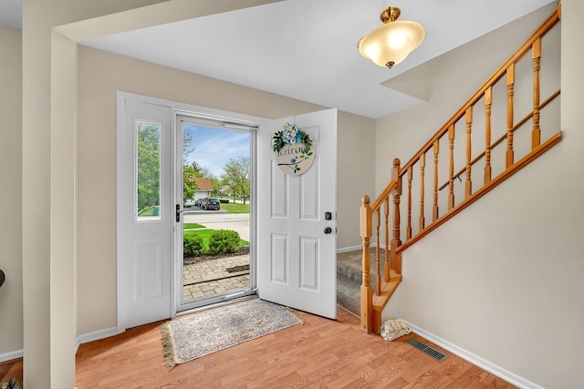entrance foyer with baseboards, light wood-style flooring, and stairs