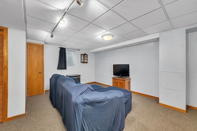 living room featuring baseboards, rail lighting, a paneled ceiling, and light carpet