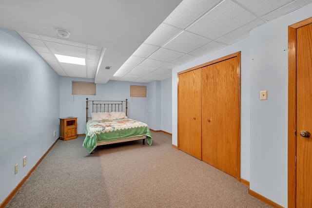 carpeted bedroom featuring baseboards, a paneled ceiling, visible vents, and a closet
