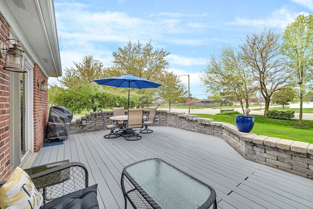 deck featuring outdoor dining area, visible vents, a lawn, and grilling area