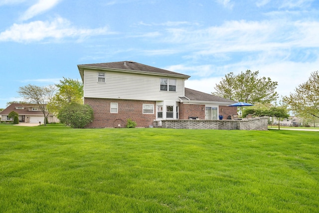 rear view of house featuring brick siding and a lawn