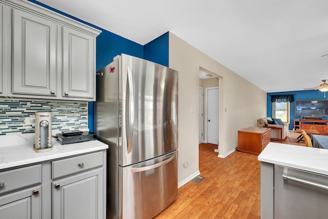 kitchen with ceiling fan, appliances with stainless steel finishes, gray cabinetry, light countertops, and open floor plan