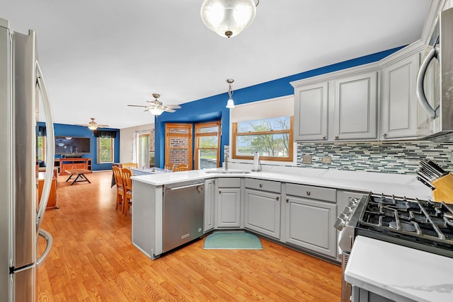 kitchen featuring light wood-type flooring, gray cabinets, backsplash, and stainless steel appliances