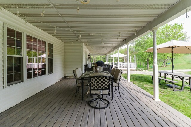 wooden terrace with outdoor dining space and a lawn