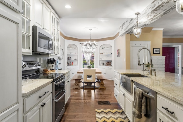 kitchen with stainless steel appliances, a chandelier, a sink, ornamental molding, and dark wood-style floors