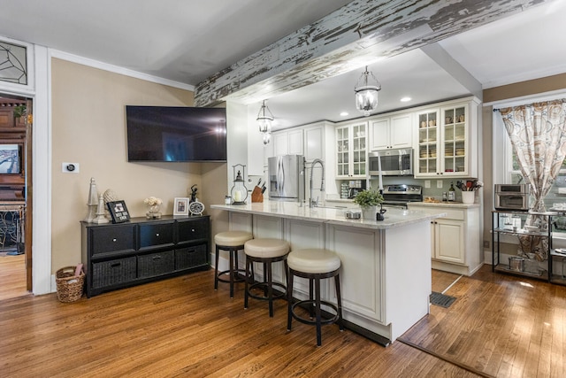 kitchen featuring appliances with stainless steel finishes, a breakfast bar area, dark wood-type flooring, crown molding, and white cabinets