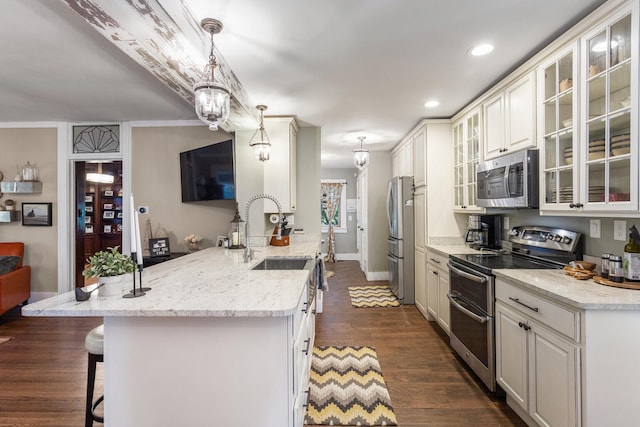 kitchen featuring stainless steel appliances, a breakfast bar area, a sink, a peninsula, and dark wood-style floors