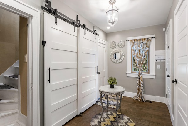 foyer featuring a barn door, baseboards, and dark wood-style floors