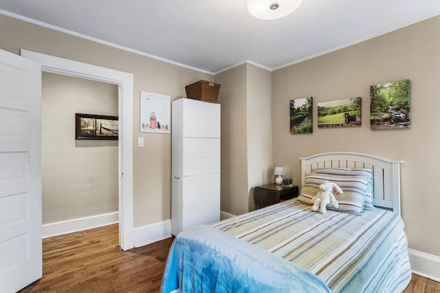 bedroom featuring wood finished floors, baseboards, and ornamental molding