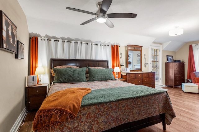 bedroom featuring wood finished floors, ceiling fan, vaulted ceiling, and baseboards