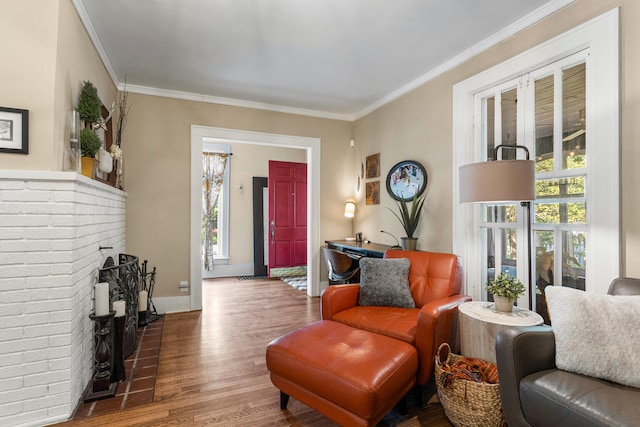 living area featuring wood finished floors, healthy amount of natural light, crown molding, baseboards, and a fireplace