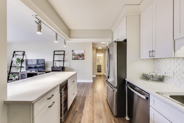 kitchen featuring beverage cooler, wood finished floors, white cabinetry, appliances with stainless steel finishes, and decorative backsplash