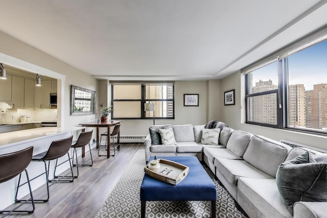 living room featuring a wealth of natural light, light wood-style floors, a view of city, and a baseboard radiator