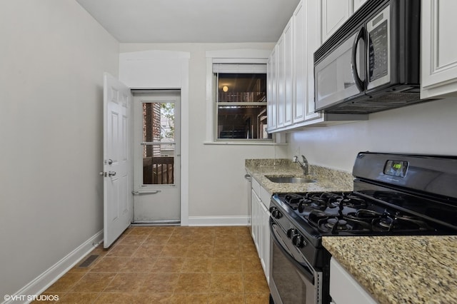 3903 N Claremont Ave Unit 1, Chicago, IL 60618 - kitchen with gas stove, a sink, black microwave, white cabinetry, and baseboards